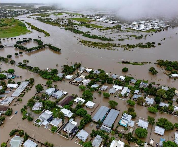 Aerial scene of a flood-stricken neighborhood, showing roads and houses submerged under water.